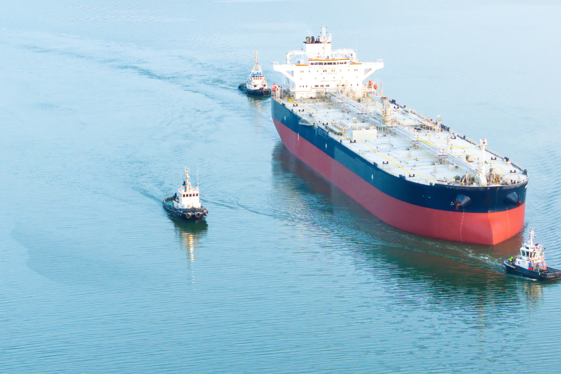 Buquetanque de importacion maritima escoltado por remolcadores representando a Oxy Services en el sector logístico.