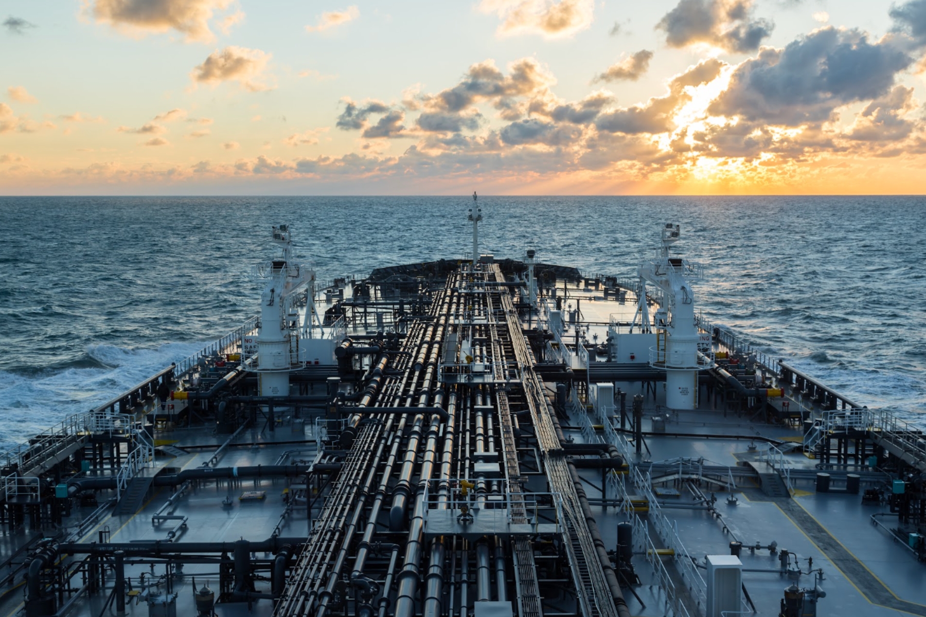 Vista frontal de la cubierta de un buque tanque navegado en mar abierto durante el atardecer, representando el transporte de energía.